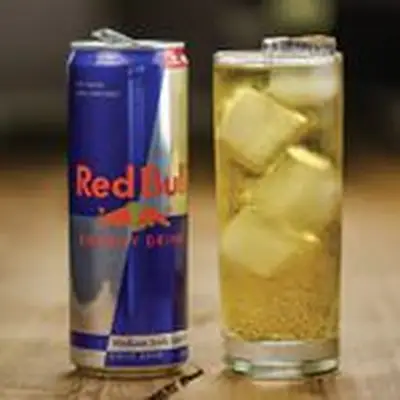 Vodka Red Bull in a glass with ice next to a can of Red Bull