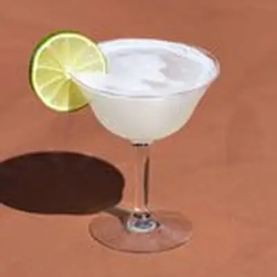 Vodka Gimlet in an etched coupe glass with lime wheel garnish, on brown background