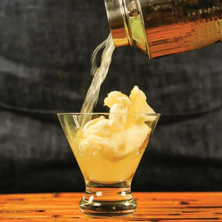 shaker pours magic cotton candy daiquiri over cotton candy into a cocktail glass 