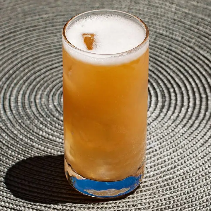 Becharita cocktail in a highball glass with ice, set on a circular placemat 