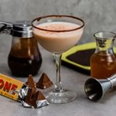 toblerone cocktail beside toblerone chocolate bar and honey syrup