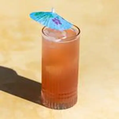 Reddish Sex on the Beach cocktail in a tall Collins glass with blue umbrella