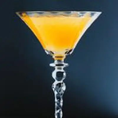 orange-colored Pineapple Upside Down Cake cocktail in a cocktail glass