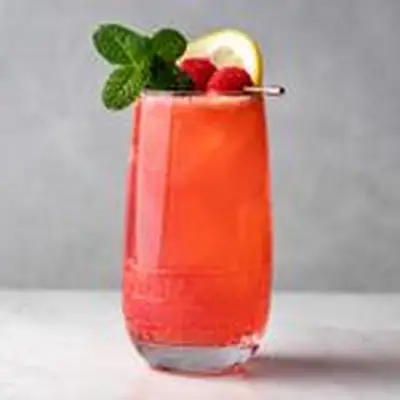 Raspberry Collins cocktail garnished with mint, lemon and raspberries