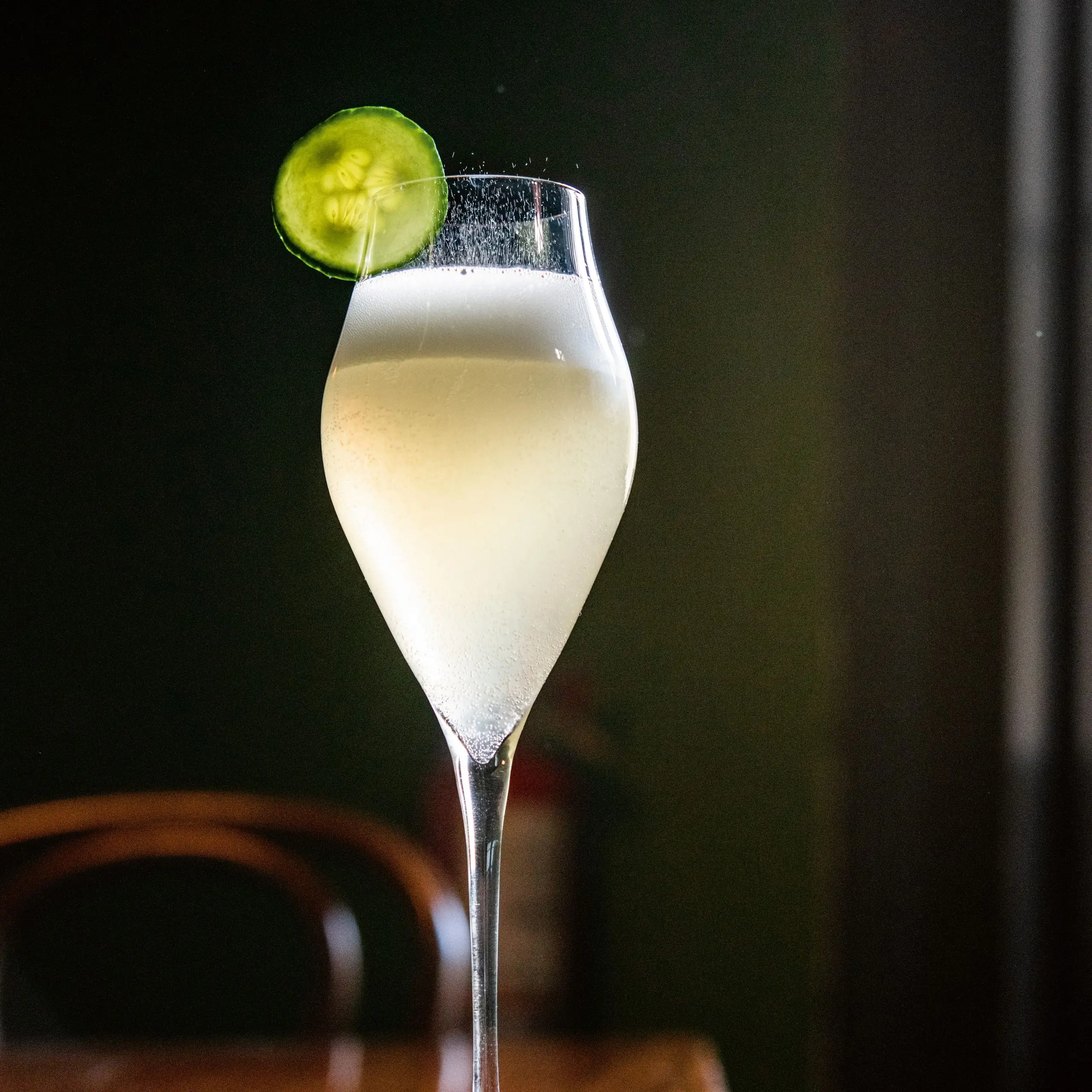 Cocktail in a flute glass garnished with a celery slice.