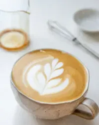 A latte made with an instant coffee espresso shot in a stoneware mug with latte art.' title='How to Make an Espresso Shot with Instant Coffee