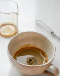 A shot of espresso made with instant coffee in a stoneware mug with a mini whisk and pitcher in the background.' title='How to Make an Espresso Shot with Instant Coffee