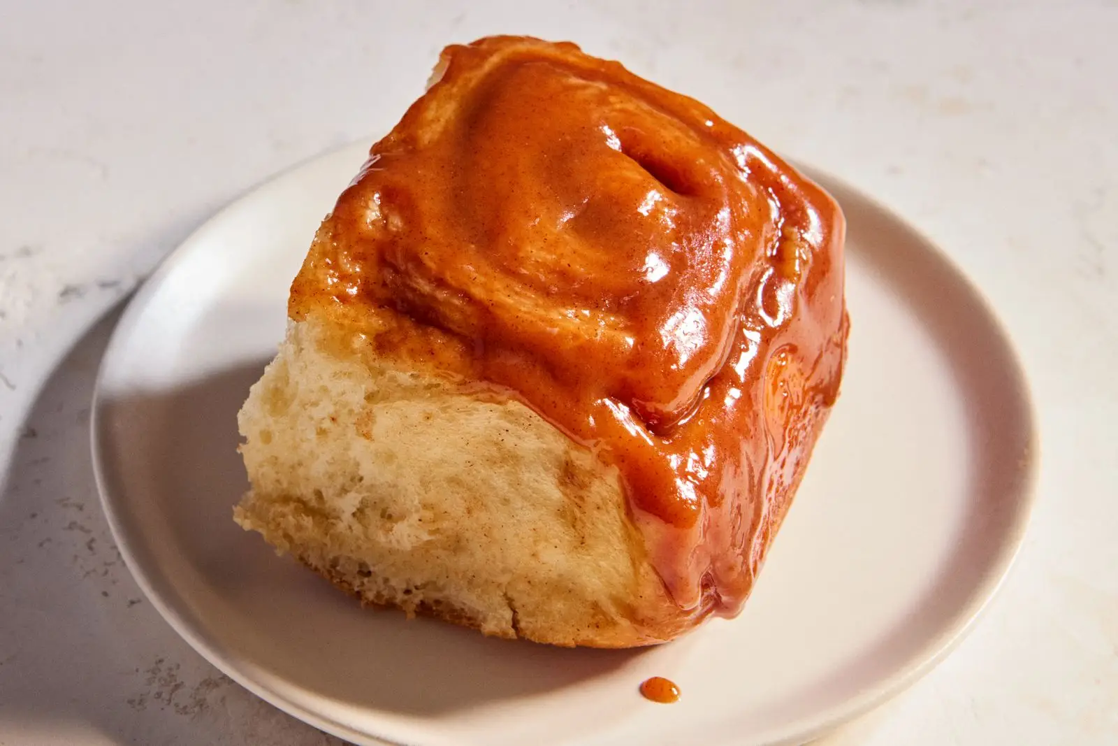 A single caramel roll on a plate.