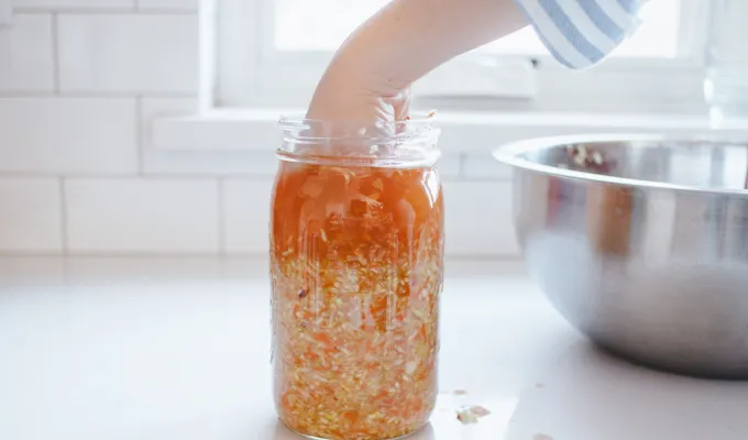Packing the spicy sauerkraut into the mason jar.' title='Easy Spicy Sauerkraut Recipe