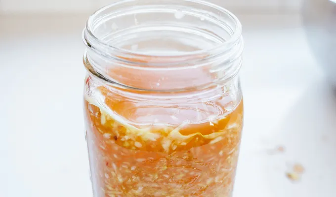 The round of leaf sitting on top of the spicy sauerkraut in the jar.' title='Easy Spicy Sauerkraut Recipe