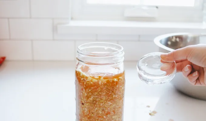 Putting a glass fermentation weight on top.' title='Easy Spicy Sauerkraut Recipe