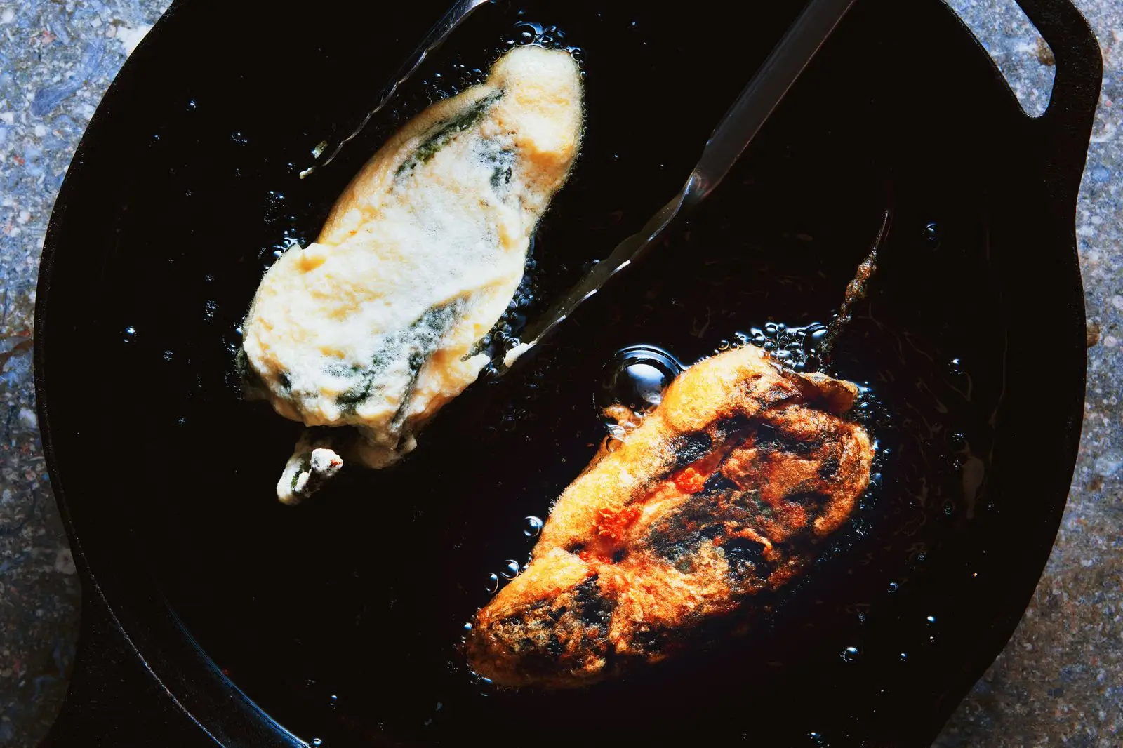 Fried cheese stuffed poblano peppers in a skillet.