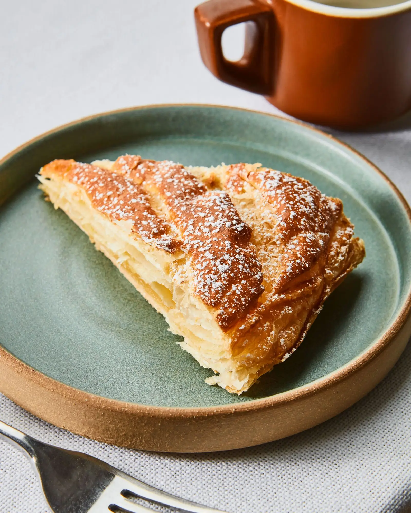 A slice of puff pastry tart filled with almond cream on a plate.