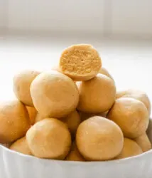 A ramekin filled with no bake powdered sugar peanut butter balls (without chocolate) with one on top cut in half so you can see the inside.' title='No Bake Peanut Butter Balls without Chocolate