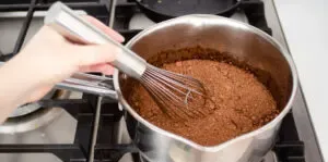 Stirring the chocolate syrup ingredients over the stove.' title='Chocolate Syrup for Coffee Recipe