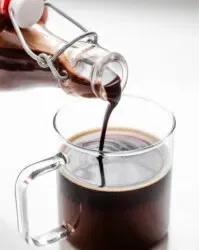Pouring chocolate syrup into a mug of coffee.' title='Chocolate Syrup for Coffee Recipe