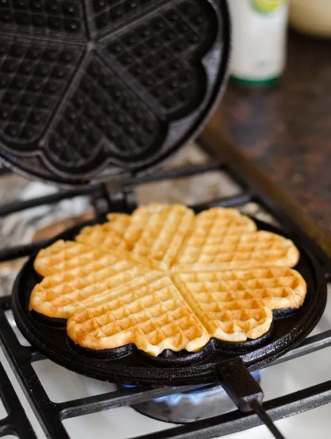 Cooking a waffle in a cast iron waffle iron.' title='Overnight Sourdough Waffles