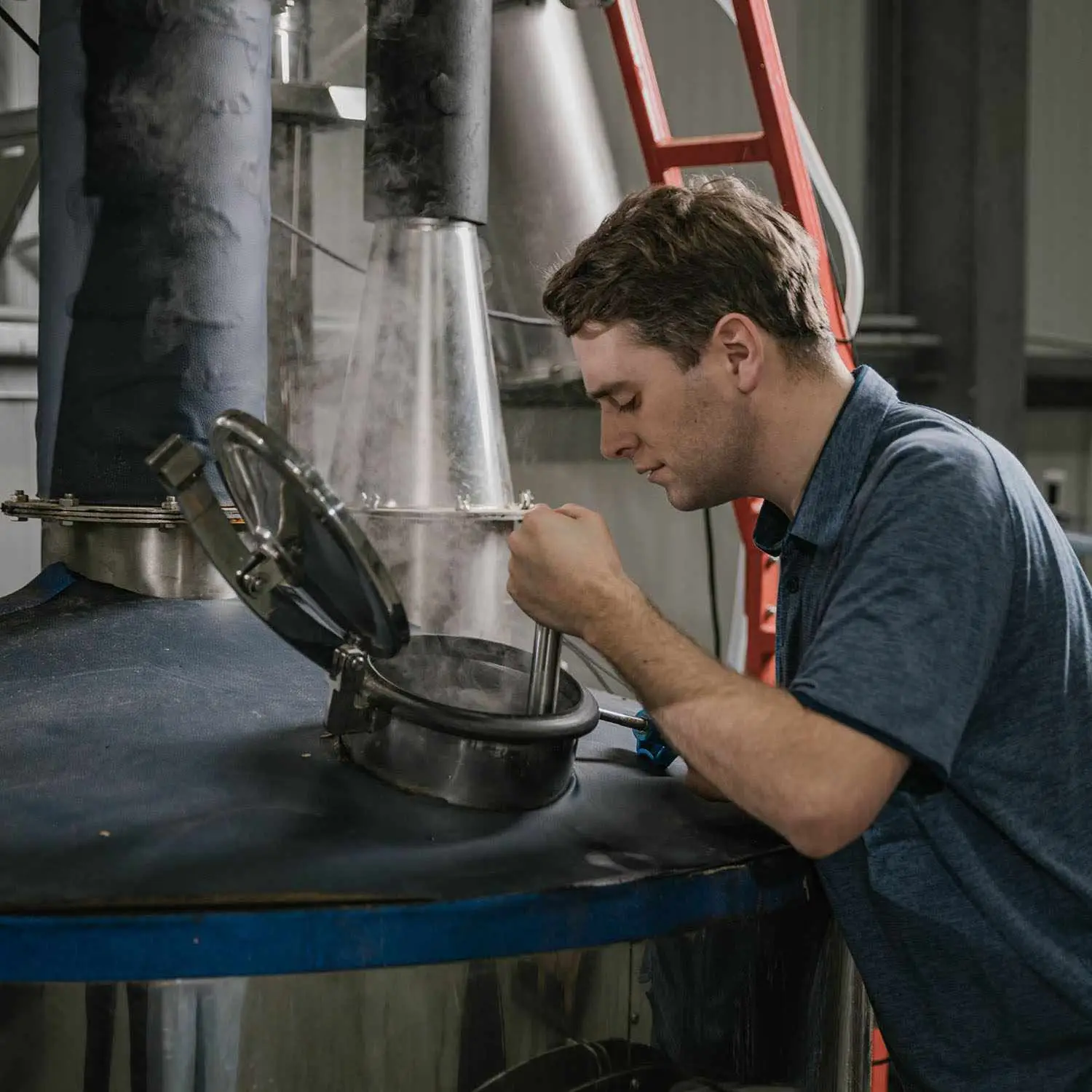 Bill Garnock at Feragaia Distillery standing over open steaming still