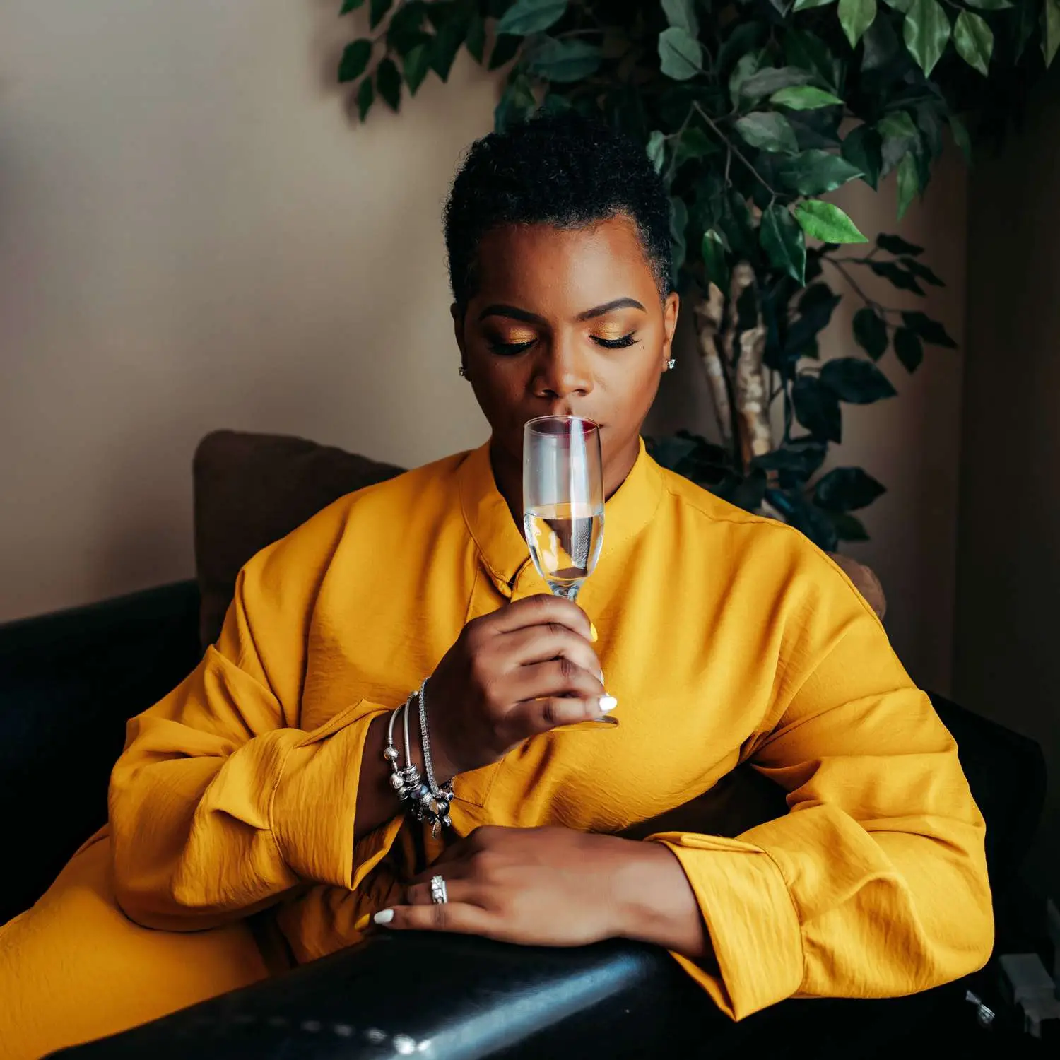 Nayana Ferguson in yellow outfit, seated, smelling tequila in tasting glass
