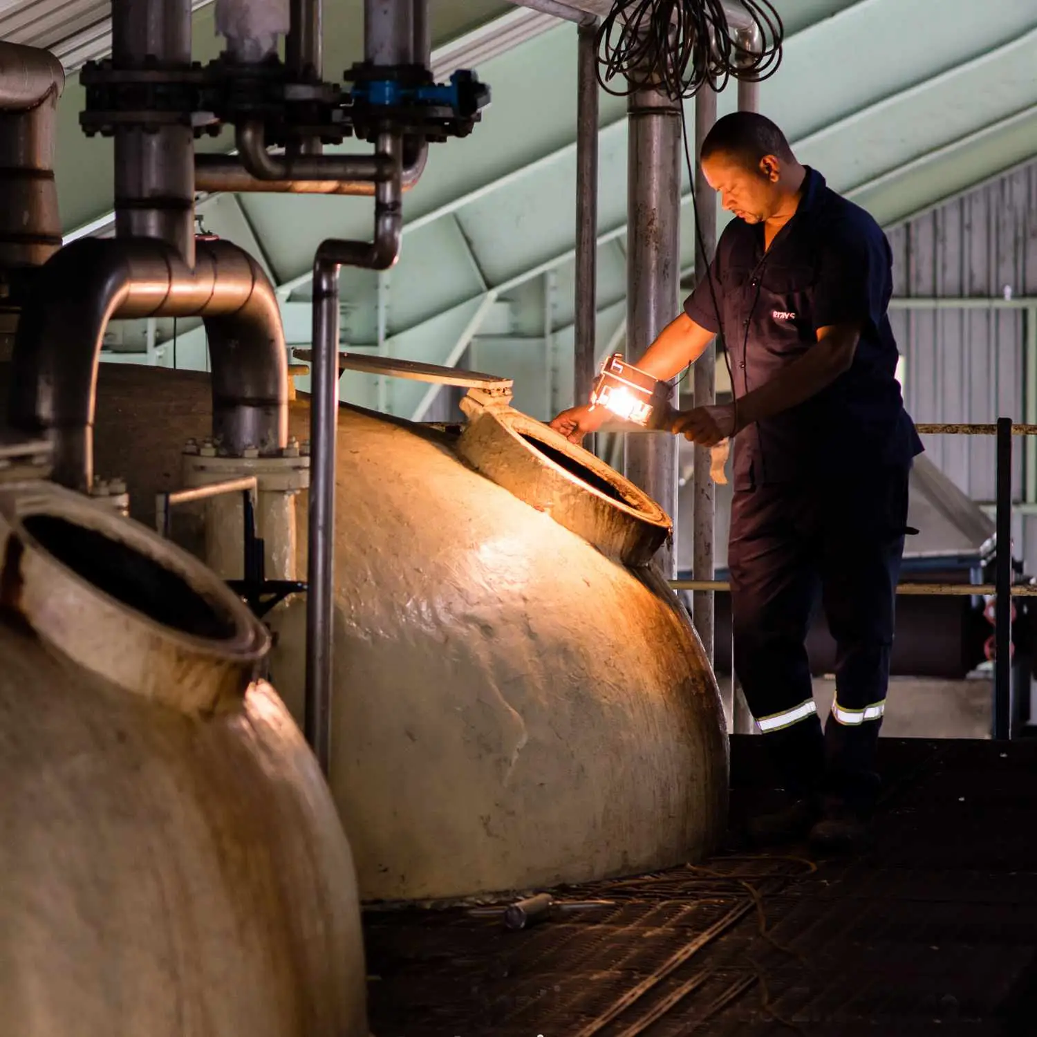 Man inspecting fermentation tanks at Equiano Rum