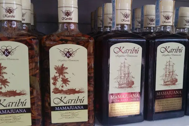 A shelf stocked with various bottles of Karibú Mamajuana; bottles on the left contain herbs and barks inside the bottle while bottles on the right side of the shelf do not