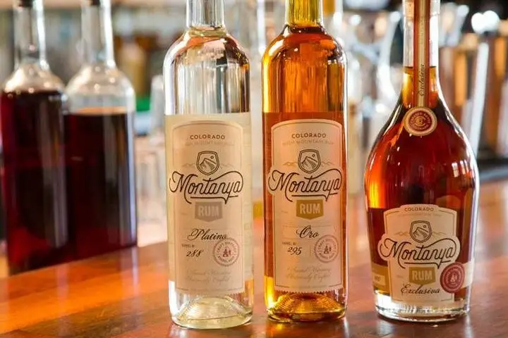 Three Montanya rum bottles lined up on a wood bar top