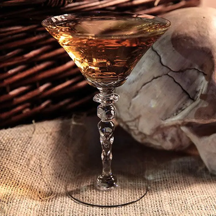 Corpse Reviver No. 1 cocktail in V shaped glass with skull in background