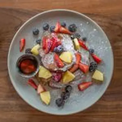 A plate of cinnamon French toast and fresh fruit dusted with powdered sugar