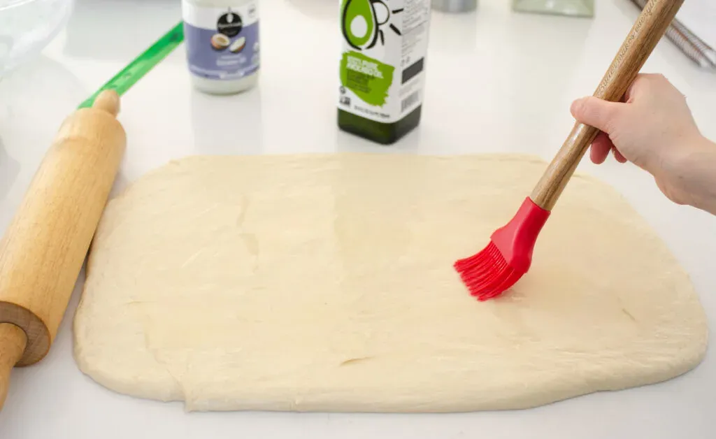 Brushing the dough with the oil in preparation for the filling.' title='Cinnamon Roll Recipe Without Milk