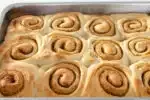 The baked cinnamon rolls without milk in a pan on a wire cooling rack.' title='Cinnamon Roll Recipe Without Milk