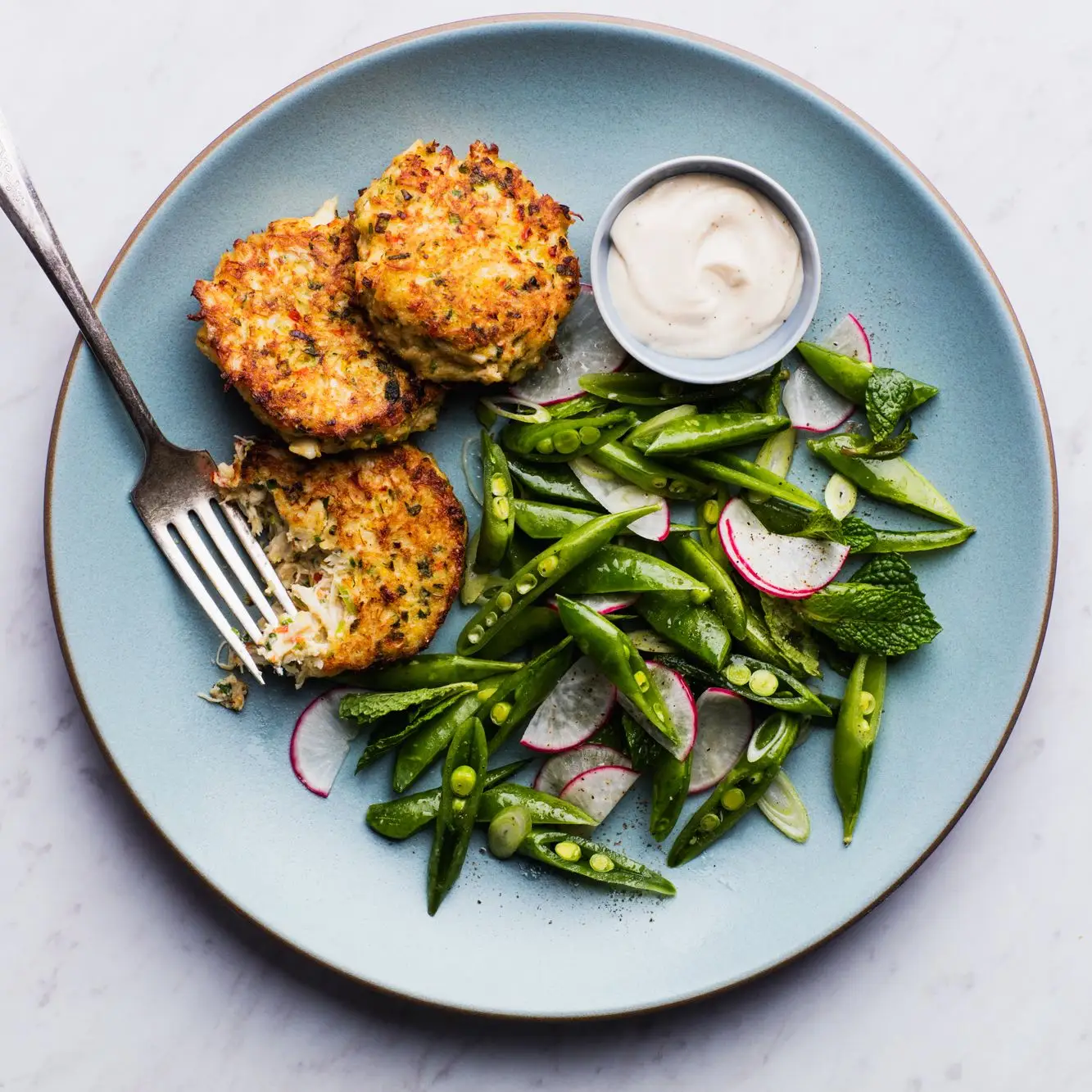 gluten free crab cakes one of our best crab recipes shown with snap pea salad on a turquoise plate
