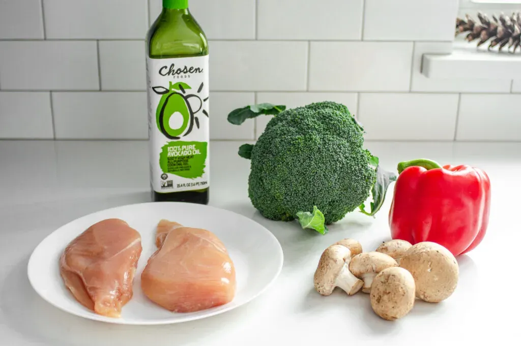 Chicken avocado oil broccoli red bell pepper and mushrooms on a white countertop with subway tile backsplash. ' title='Healthy Chicken Stir Fry Recipe