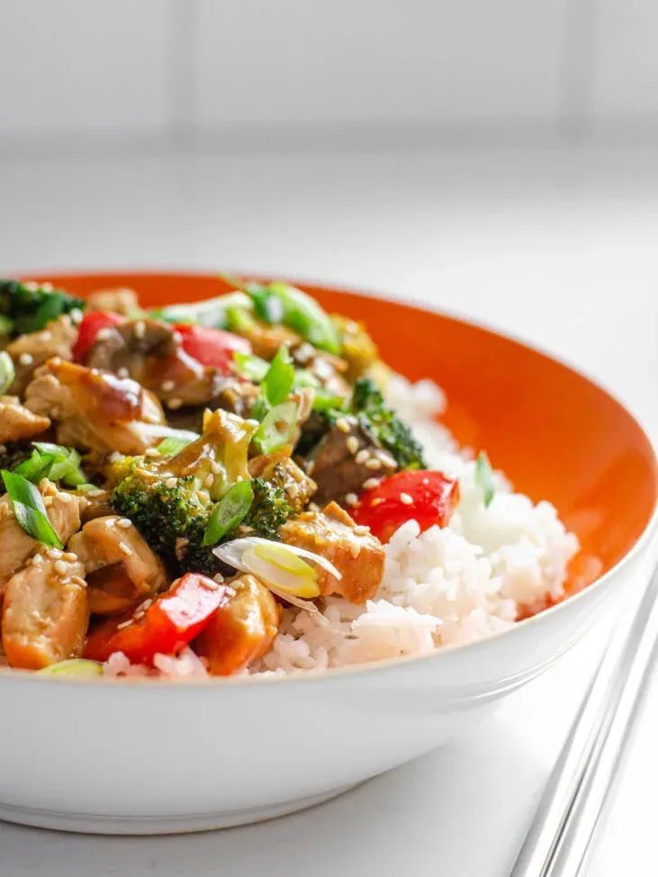 An orange bowl of rice with chicken stir fry on top. Learn how to make my healthy chicken stir fry recipe with these step by step instructions!' title='Healthy Chicken Stir Fry Recipe