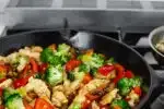 A large cast iron skillet filled with healthy chicken stir fry with loads of veggies.' title='Healthy Chicken Stir Fry Recipe