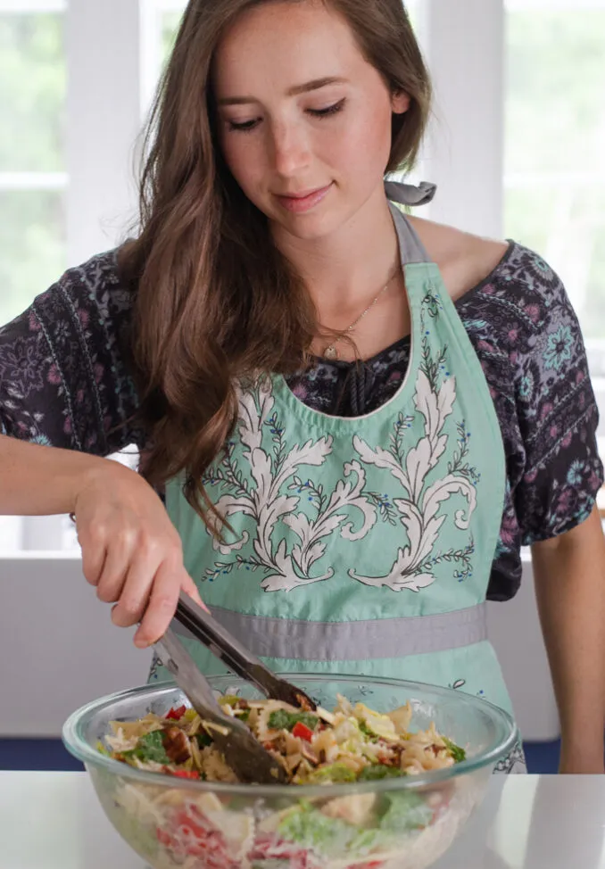 Mixing together the ingredients for a BLT bowtie pasta salad.' title='BLT Bowtie Pasta Salad