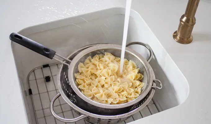 Rinsing the cooked bowtie pasta with cold water.' title='BLT Bowtie Pasta Salad