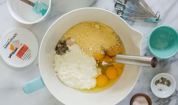 Eggs parmesan cheese cottage cheese salt and pepper in a mixing bowl with a whisk.' title='Egg Muffin Cups with Cottage Cheese Bacon and Peppers