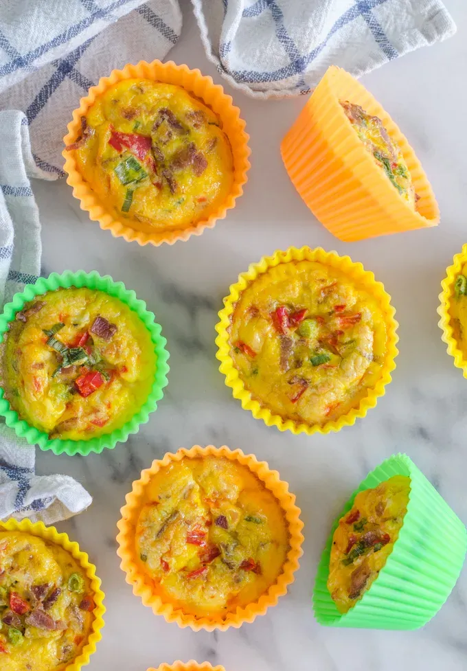 From above shot of several egg muffin cups on a marble surface with a checked tea towel.' title='Egg Muffin Cups with Cottage Cheese Bacon and Peppers