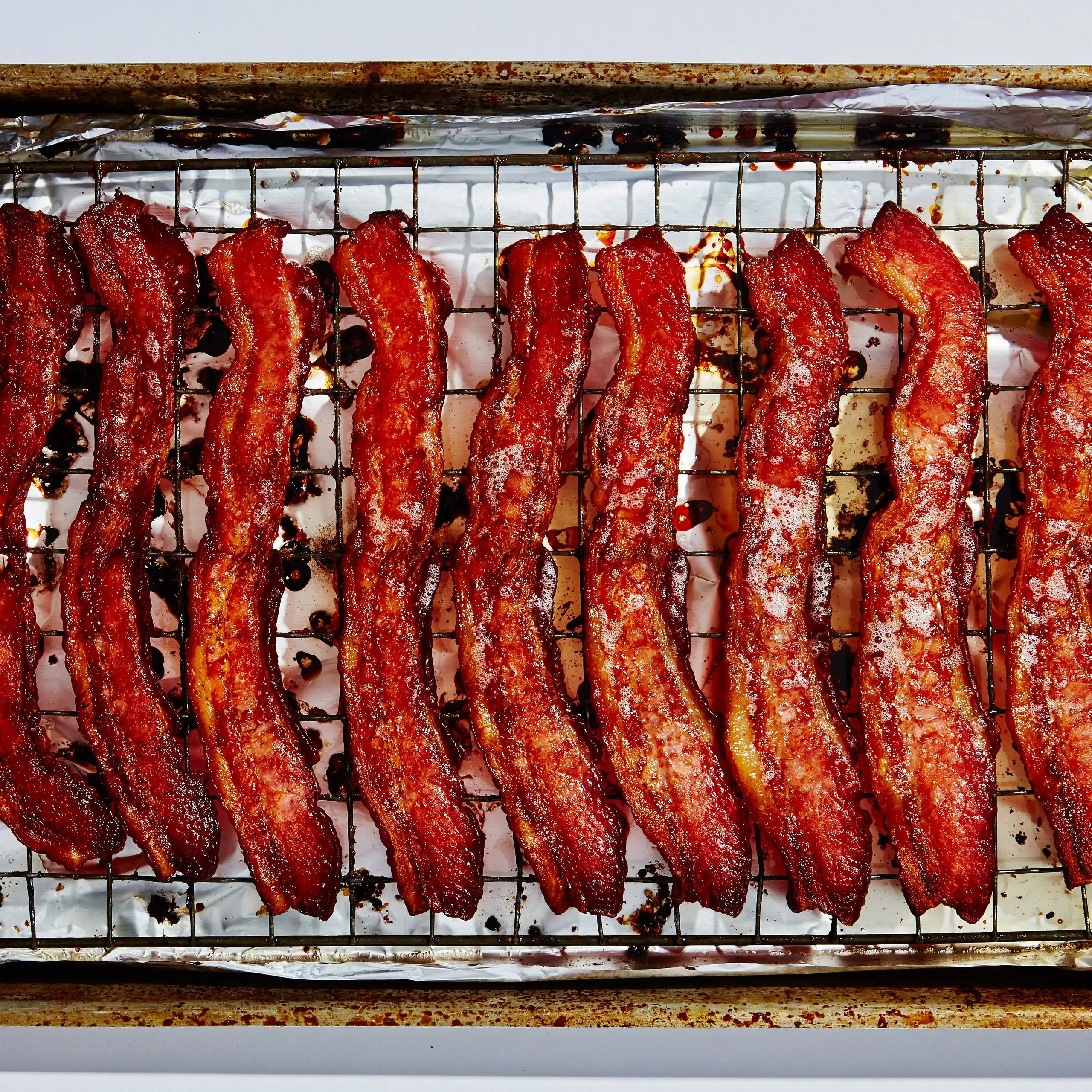 Cooked bacon on a wirerack on a foillined sheet tray.
