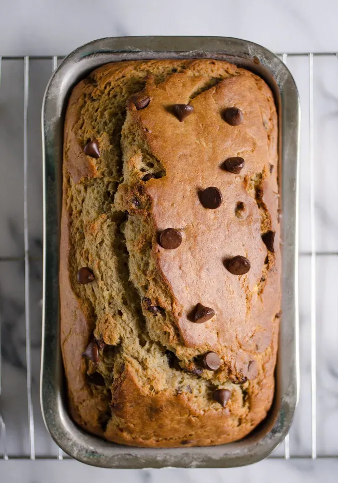 Sourdough banana bread in loaf pan on a cooling rack on a marble surface.' title='Sourdough Banana Bread