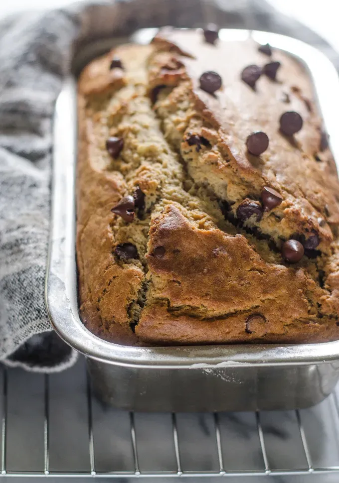 Sourdough banana bread in loaf pan on a cooling rack on a marble surface.' title='Sourdough Banana Bread