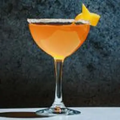 orange-hued Brandy Crusta in a coupe glass with a sugared rim and lemon twist