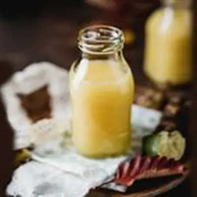pineapple cordial in a glass bottle beside a lime wedge and leaf