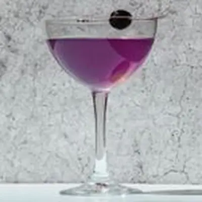 Purple-hued Aviation cocktail in a coupe with a cherry garnish