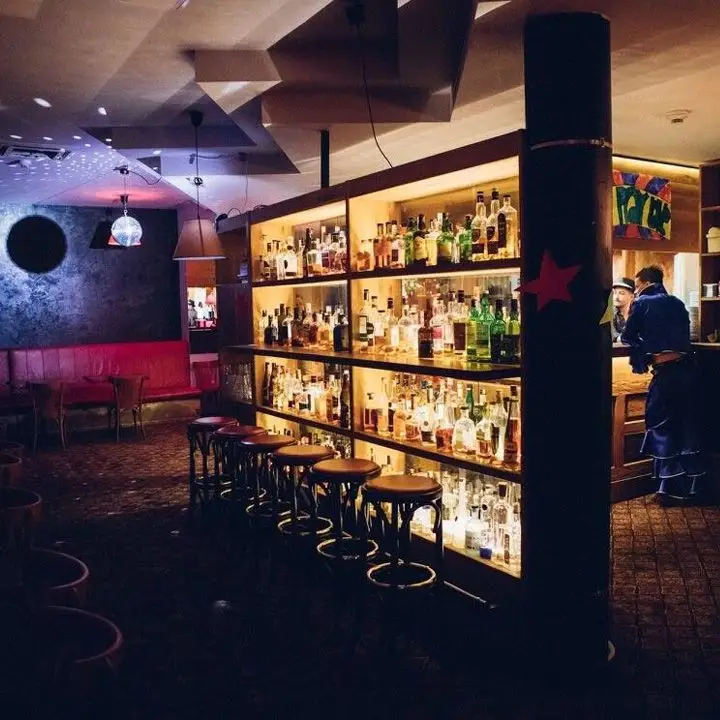 The Bar Which Doesnt Exist, looking onto a beautifully backlit collection of booze bottles with stools in front of it