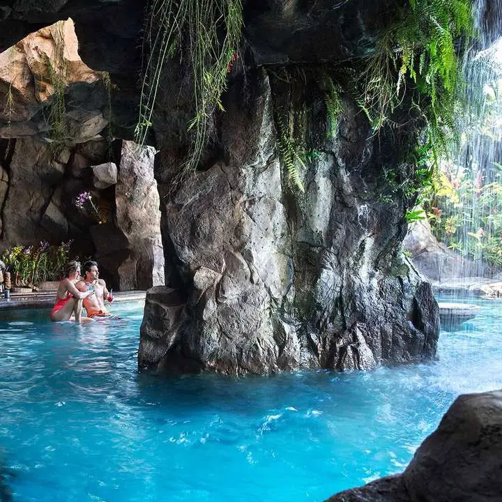 Grand Wailea swim-up bar in maui. Bright blue surrouds a rock pillar in the center. light streams in from above.