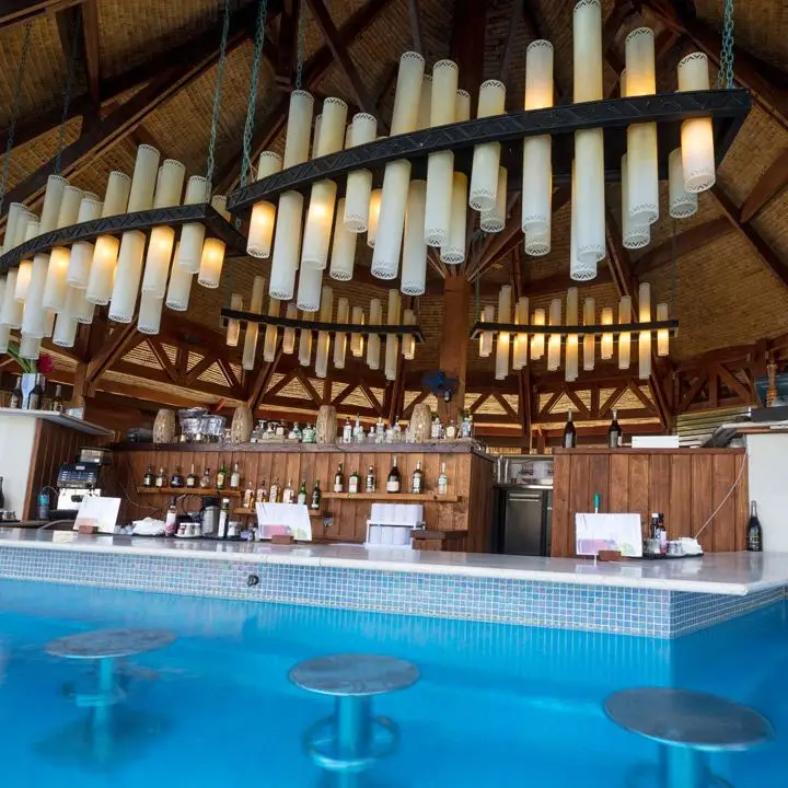 The St. Regis Bora Bora swim-up bar. Pillar-like light fixtures hang in tight groups from the ceiling