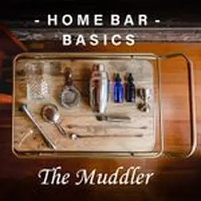 Aerial view of a wooden bar cart with various supplies and tools laid out, including a mixing glass, strainers, bar spoon, jigger and muddler