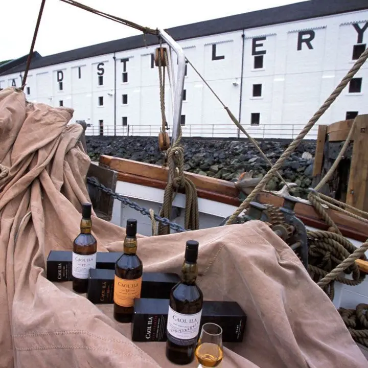 Caol Ila Distillery with a bunch of their bottles laid out artfully on a tarp in a boat