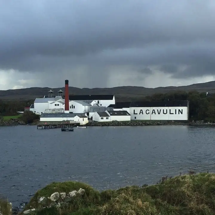 Lagavulin Distillery, seen from far away with the full whitewashed distillery in the background voer open water